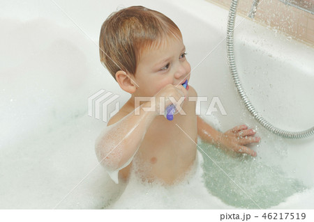 cute two year old baby taking a bath with foam and brushing teeth 46217519