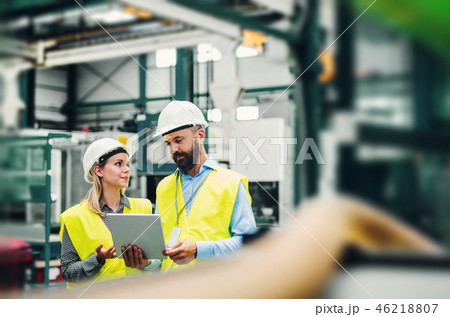 A portrait of an industrial man and woman engineer with tablet in a factory. A portrait of an industrial man and woman engineer with tablet in a factory. 46218807