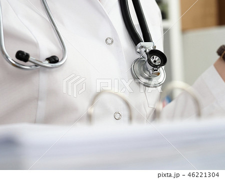 Stethoscope lying on female therapeutist doctor chest 46221304