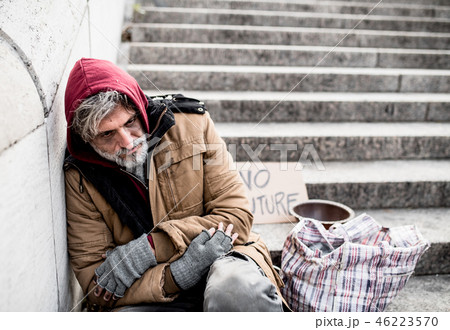 Homeless beggar man sitting outdoors in city asking for money donation. 46223570