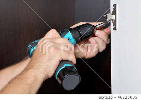 assembler is screwing cordless screwdriver  46225035