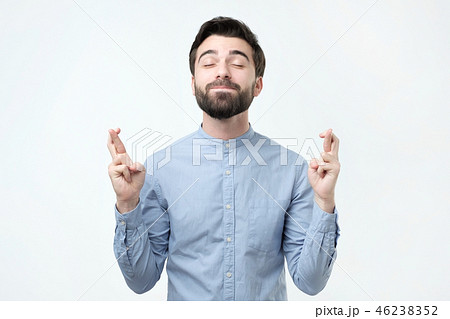 Hispanic man standing with crossed fingers Hispanic man standing with crossed fingers 46238352