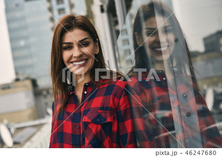 Smiling woman is standing on veranda outdoors Smiling woman is standing on veranda outdoors 46247680