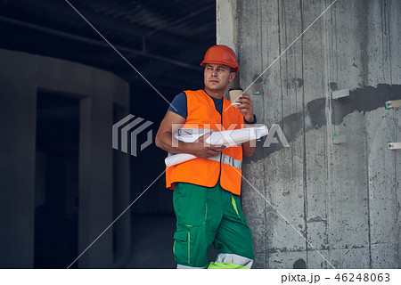 Thoughtful master builder leaning to the wall and drinking coffee 46248063