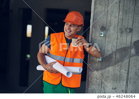 Cheerful builder smiling and holding carton cup of coffee 46248064