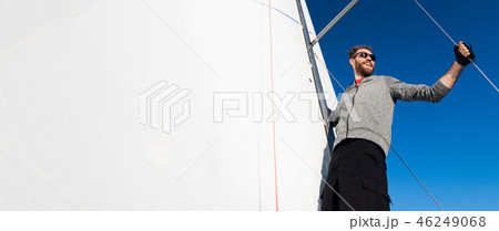 Yacht captain with a beard stands on sail boom on a sailing yacht, holding the rope in his hand and Yacht captain with a beard stands on sail boom on a sailing yacht, holding the rope in his hand and 46249068