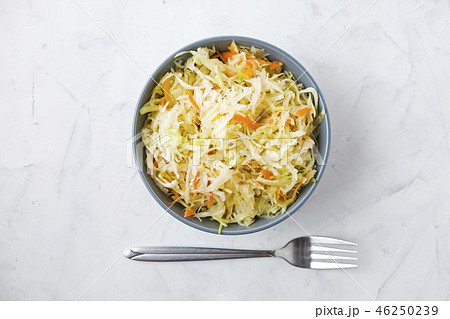 Fork and bowl of fermented cabbage on plaster surf 46250239