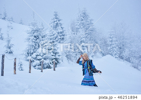 Attractive blond girl in long blue dress, embroidered warm sleeveless fur coat outdoor in deep snow. 46251894