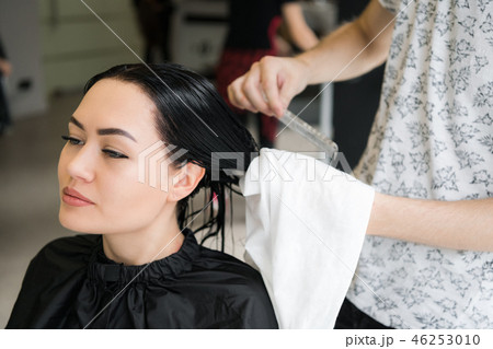 Hairdresser wrapping towel on customer's head. Brunette woman getting hair treatment in a salon. 46253010