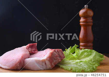 Raw steak on rustic cutting board with salt, pepper and grinder for spices. Black Background for Raw steak on rustic cutting board with salt, pepper and grinder for spices. Black Background for 46254751