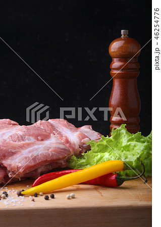 Raw Ribs on a rustic cutting board with salt, pepper and grinder for spices . Black Background for Raw Ribs on a rustic cutting board with salt, pepper and grinder for spices . Black Background for 46254776