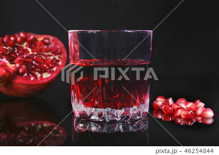 Glass with pomegranate juice Pomegranate seeds and Beautiful ripe pomegranate on black mirror 46254844