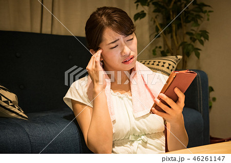 部屋でスマホを見る疲れ目の若い日本人女性 部屋でスマホを見る疲れ目の若い日本人女性 46261147