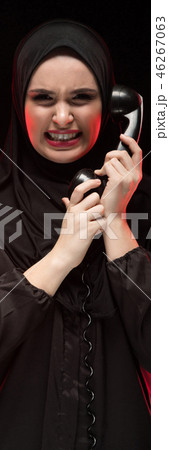 Portrait of beautiful serious scared young muslim woman wearing black hijab screaming calling for 46267063