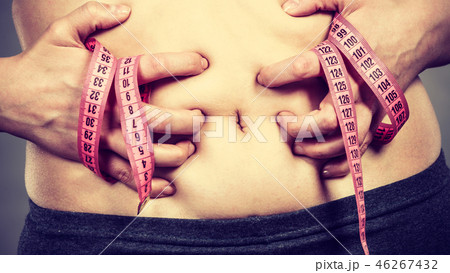 Woman touching stomach holding measuring tape Woman touching stomach holding measuring tape 46267432