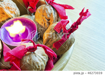 purple candle with decorated wallnuts in a bowl. 46273039