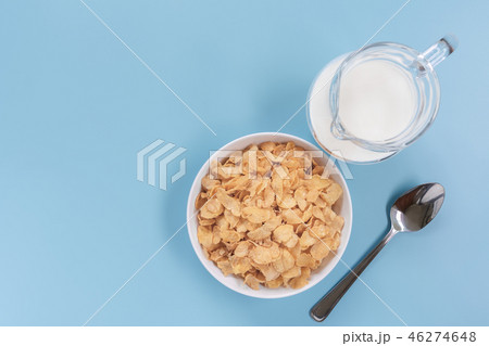 top view of corn flakes in a bowl with jug of milk 46274648