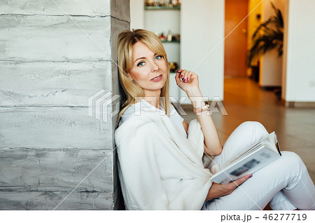 Young woman reading book on floor near light wall 46277719