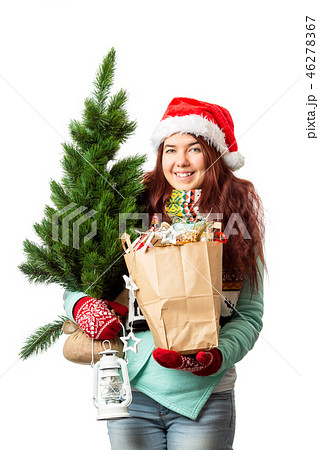 Photo of woman in Santa hat with Christmas tree, paper bag inhands Photo of woman in Santa hat with Christmas tree, paper bag inhands 46278367