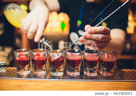 Bartender is pouring tequila into glass against the background of the bar. Bartender is pouring tequila into glass against the background of the bar. 46280001