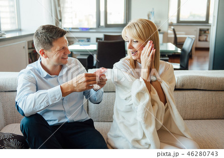 Young woman receiving a surprise gift red box from her boyfriend on sofa 46280743