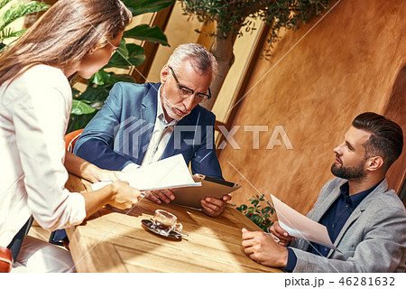 Business lunch. Three people in the restaurant sitting at table discussing project joyful close-up 46281632