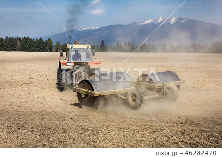 Tractor pulling heavy metal roller on dry field, Tractor pulling heavy metal roller on dry field, 46282470