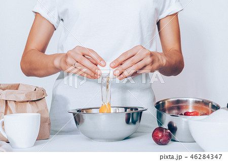 Woman wearing white t-shirt breaking raw egg 46284347