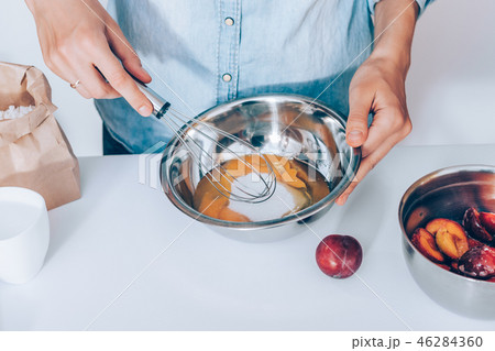 Close-up female's hands whisk raw eggs with sugar Close-up female's hands whisk raw eggs with sugar 46284360