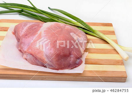 pork steaks with fat. Meat is on wooden board with spice as pepper and green spring onion. Ready for 46284755