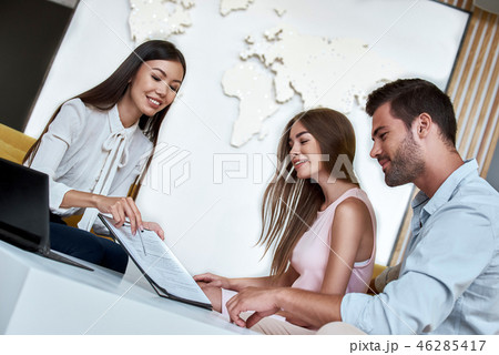 Couple sitting with manager at the travel agency office and reviewing contract 46285417