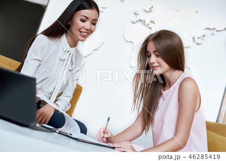 Young woman signing contract for a trip with agent Young woman signing contract for a trip with agent 46285419