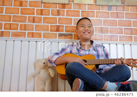 asian kid boy child playing guitar ukulele. children leisure activity asian kid boy child playing guitar ukulele. children leisure activity 46286475