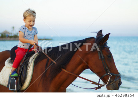 Cute little boy rides a horse on the beach. Copy space 46299354
