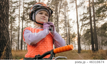 One caucasian children walk with bike in autumn park. Little girl walking black orange cycle in 46310674