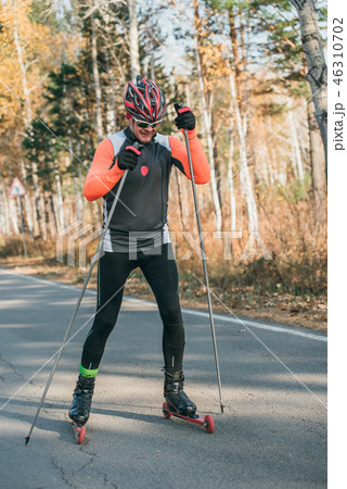 Training an athlete on the roller skaters. Biathlon ride on the roller skis with ski poles, in the 46310702