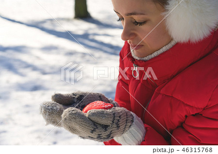 Hands in Knitted Mittens holding Steaming Cup of Hot Tea on Snowy Winter Morning Outdoors. Woman 46315768