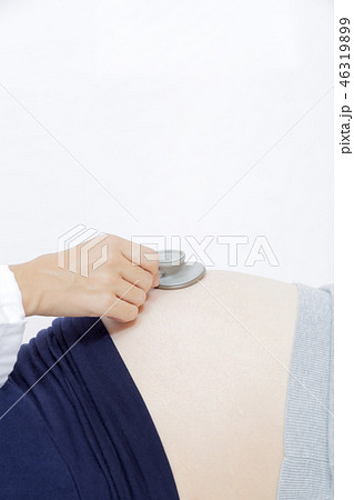 妊婦の大きなお腹を聴診器で診察する女医の手元のアップ。妊娠、診察、臨月、検査,産婦人科、女医イメージ 46319899