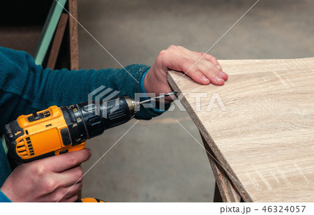 Assembling furniture from chipboard, using a cordless screwdriver, close up. 46324057