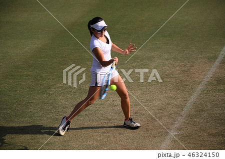 天然芝のコートでフォアハンドストロークを打つジュニアテニスプレイヤー 46324150
