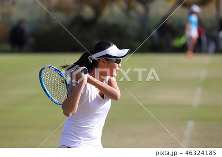 天然芝のコートでバックハンドストロークを打つジュニアテニスプレイヤー 46324185