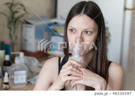 Young woman turning on respiratory inhaler Young woman turning on respiratory inhaler 46330397
