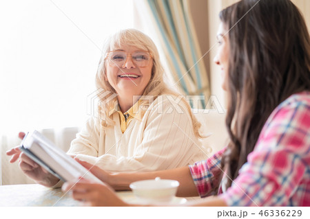 Senior mother and daughter read a book over a cup of tea Senior mother and daughter read a book over a cup of tea 46336229