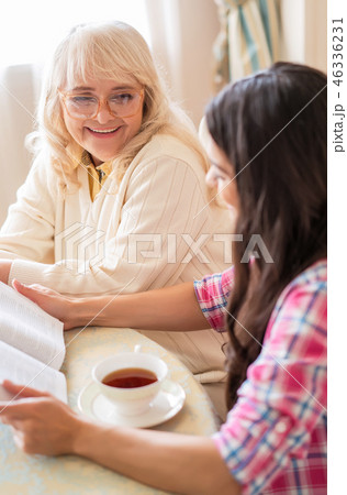 Senior mother and daughter read a book over a cup of tea Senior mother and daughter read a book over a cup of tea 46336231