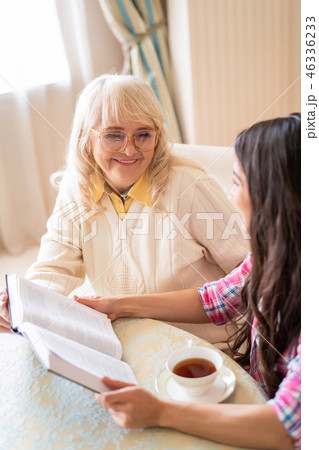 Senior mother and daughter read a book over a cup of tea 46336233