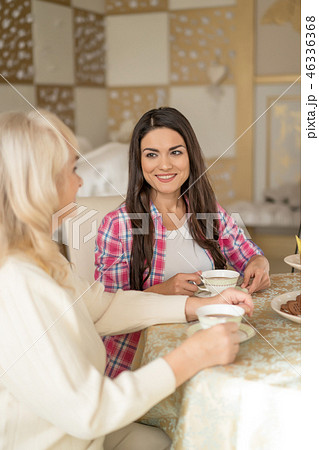 Portrait of pretty woman drinking tea and talking with her old mother Portrait of pretty woman drinking tea and talking with her old mother 46336368