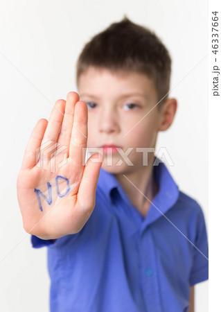 Teen little boy making stop sign with word no on open palm Teen little boy making stop sign with word no on open palm 46337664