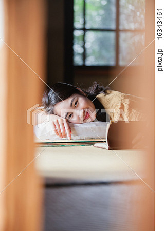 旅行先で畳に寝転び本を読む若い女性 46343464