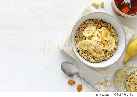 Bowl of oatmeal with banana against white table 46346946