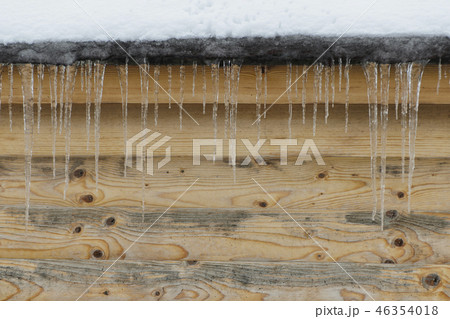 Icicles on a background of brown wooden wal Icicles on a background of brown wooden wal 46354018